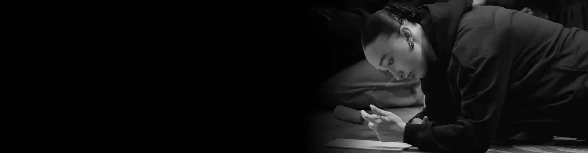 Dancer lying on the studio floor, reading notes before class