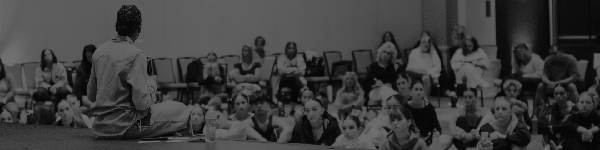 A DanceForward speaker seated on stage in front of a room of dancers